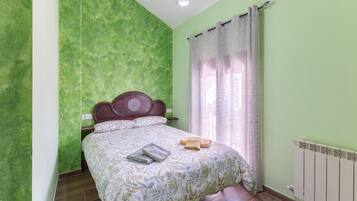 A room with a bed, a wooden headboard, a radiator, and a window with curtains.