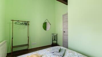 Una habitación con cama, perchero, espejo y puerta.