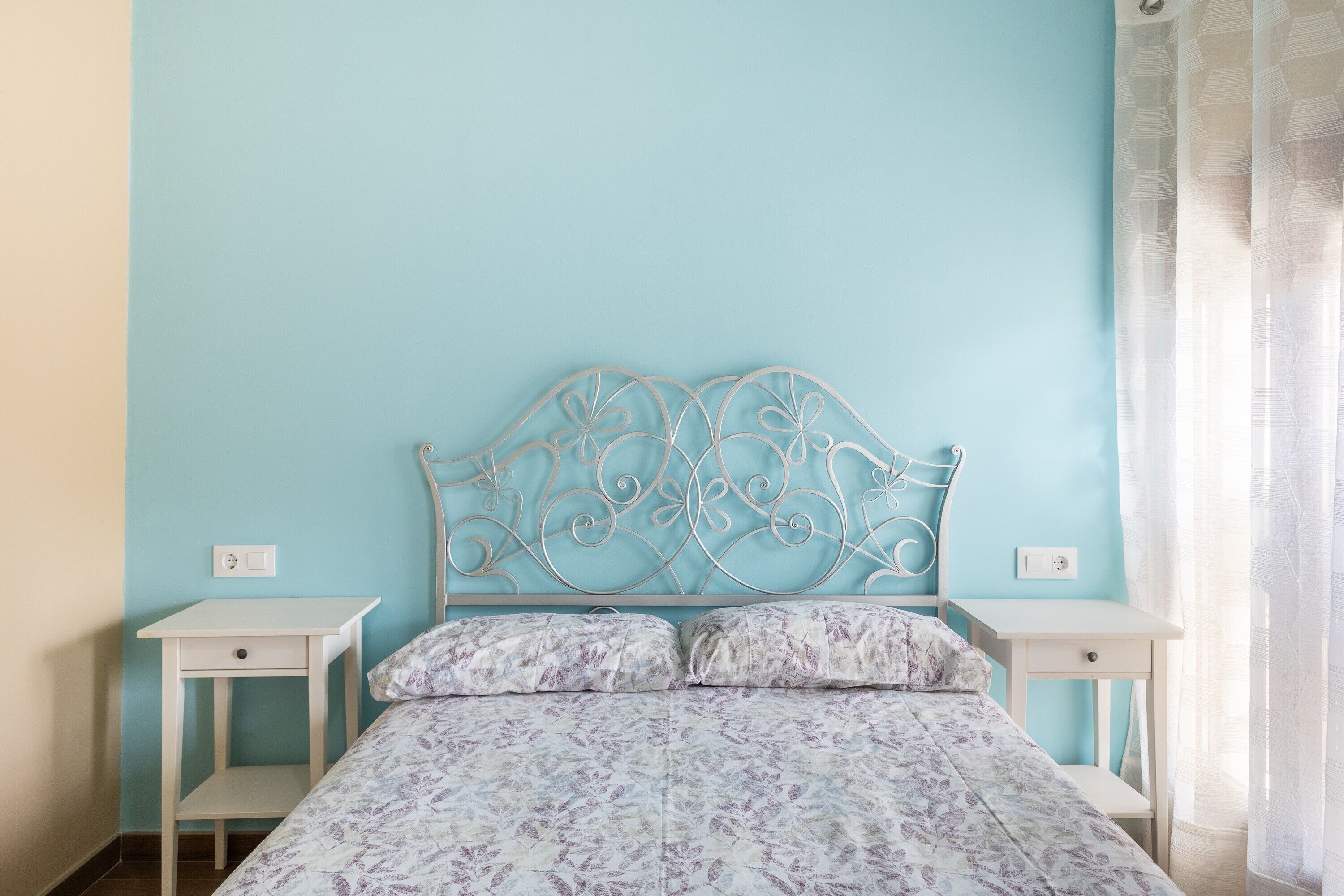 A bedroom with a bed, two bedside tables, and a wall-mounted headboard.