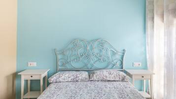 A bedroom with a bed, two bedside tables, and a wall-mounted headboard.