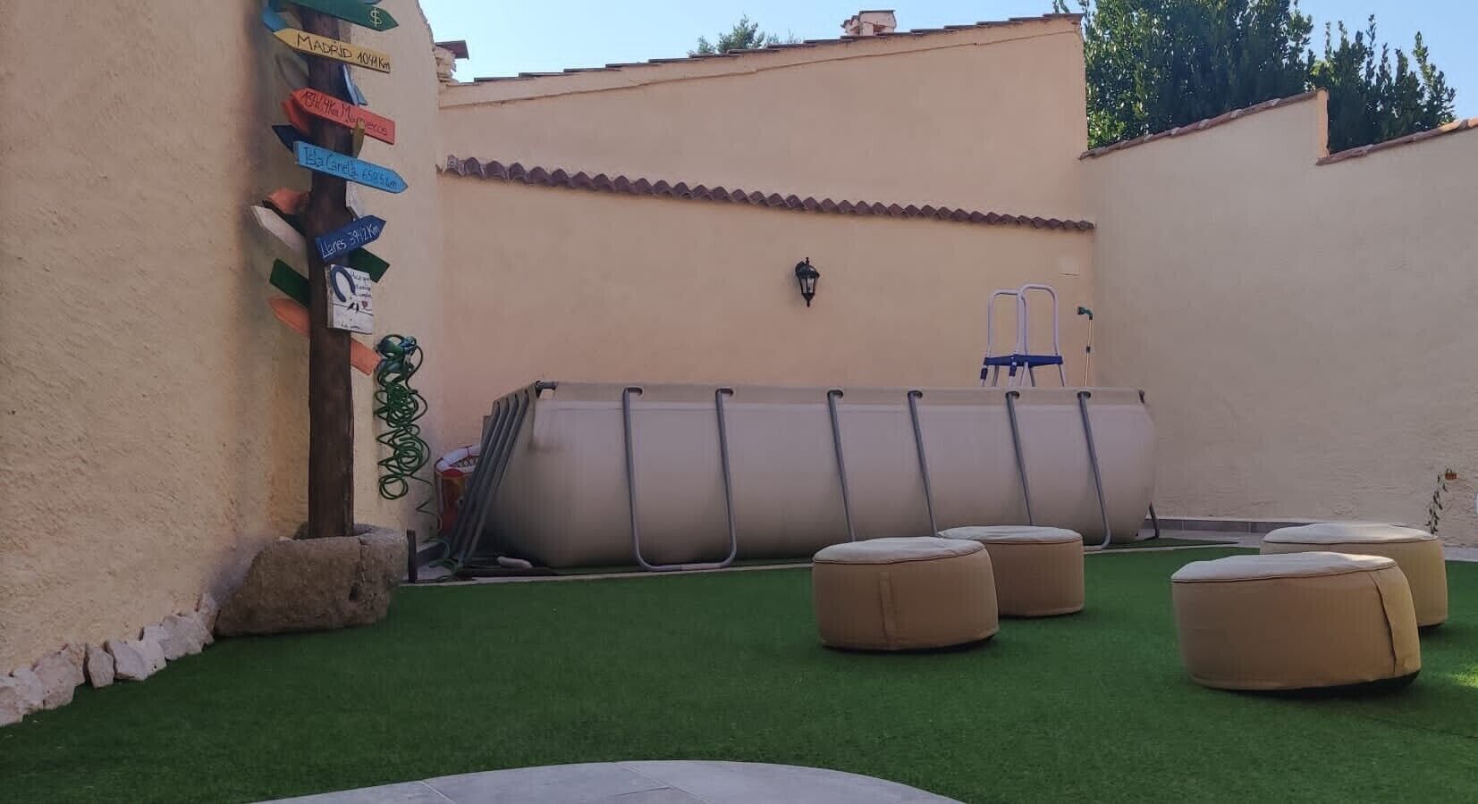 A patio with artificial grass, outdoor seating, and a wall with directional signs.