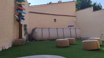 A patio with artificial grass, outdoor seating, and a wall with directional signs.