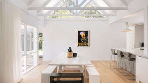 A modern kitchen with a white countertop, bar stools, and a dining table with benches.