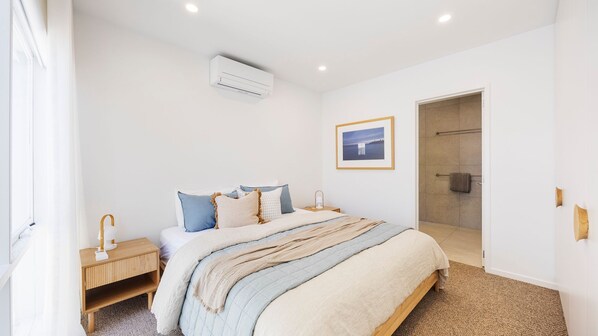 A bedroom with a bed, bedside table, and a picture on the wall.