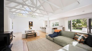 Een ruime woonkamer met een bank, een eettafel en een keuken op de achtergrond.