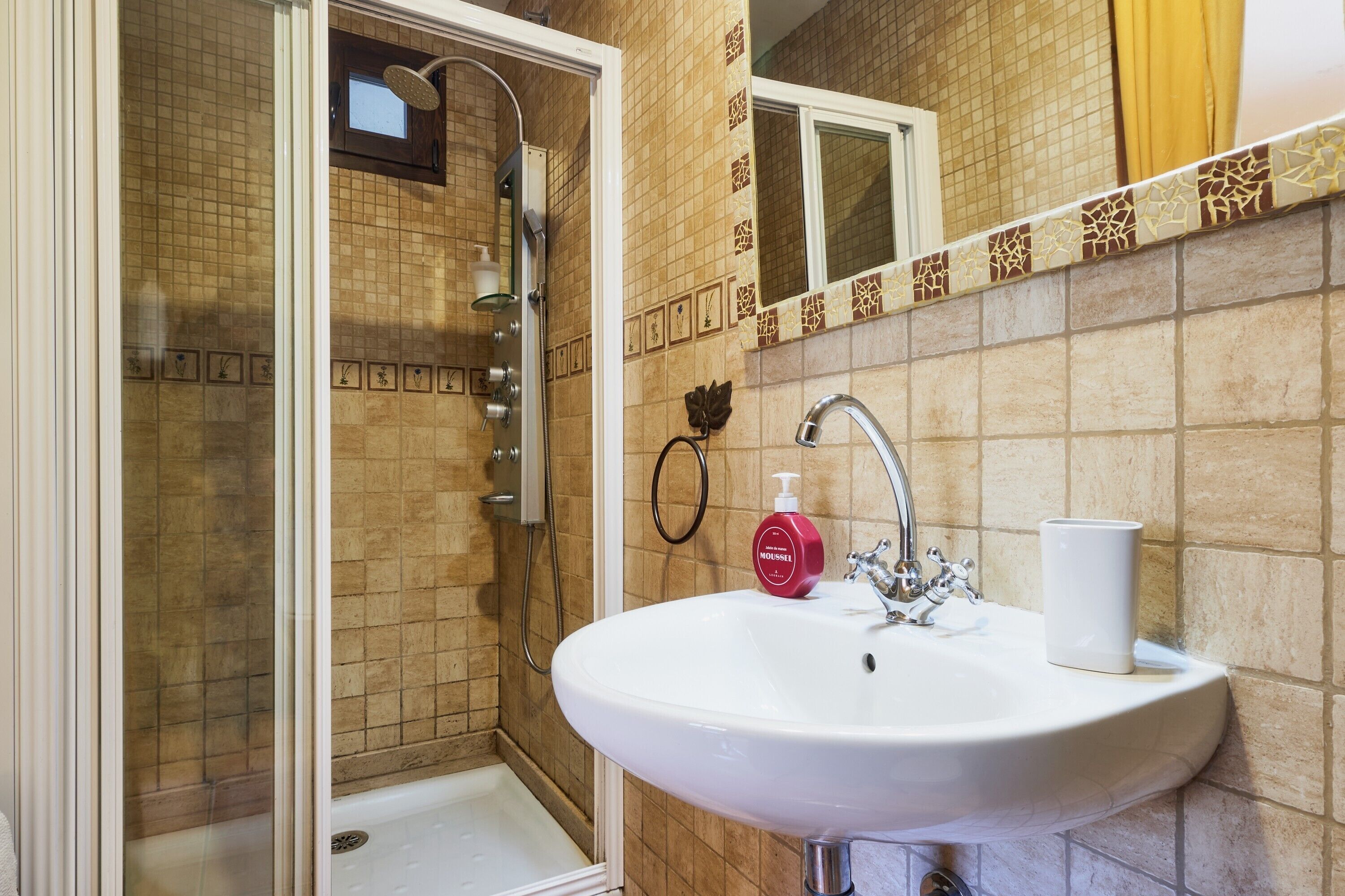 Un baño con ducha, lavamanos y espejo.