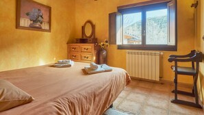 Quarto com cama, cômoda, espelho, janela com vista e radiador.