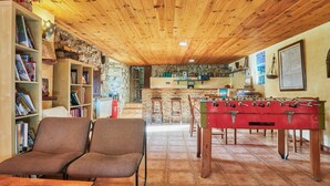 Um quarto aconchegante com mesa de pebolim, área de bar e espaço de estar com estantes.