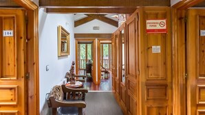 Un pasillo de madera con una zona de comedor, puertas de madera y un cartel que prohíbe fumar.