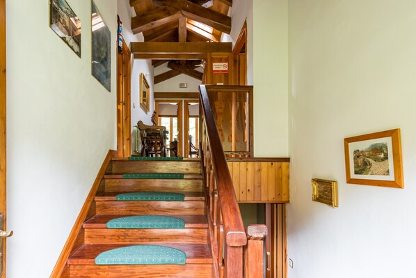 Eine Holztreppe mit grünen Stufen führt zu einem Raum mit einem Esstisch und Stühlen.