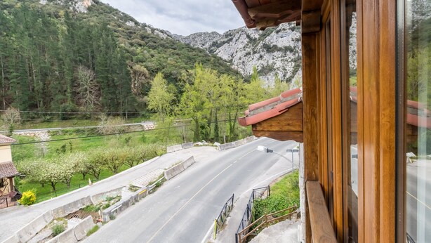 Una carretera de montaña con un edificio de madera y vistas del paisaje circundante.