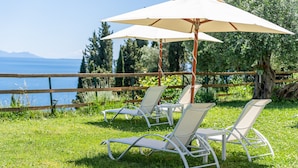 Outdoor seating with umbrellas, a wooden fence, and a view of the water.