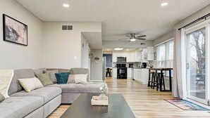 A modern living room with a sofa, coffee table, and a kitchen in the background.
