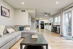 A modern living room with a sofa, coffee table, and a kitchen in the background.
