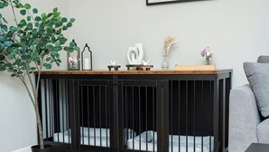 A black metal pet enclosure with a wooden top shelf, a potted plant, and decorative items.