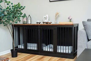 A black metal pet enclosure with a wooden top shelf, a potted plant, and decorative items.