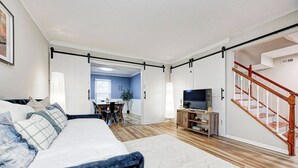 Un dormitori modern amb un llit, un moble televisió i una escala.