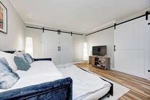 A bedroom with a bed, wardrobe, TV stand, and a large wardrobe with sliding doors.