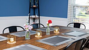 A dining table with a geometric patterned runner, a vase with flowers, and candle holders.