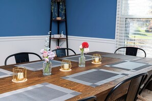 A dining table with a geometric patterned runner, a vase with flowers, and candle holders.
