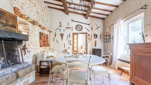 A rustic dining room with a stone wall, wooden beams, a fireplace, and a variety of tools hanging on the wall. - Holiday Home 'Maison - Les Bergeries De Danielle' with Private Pool, Private Terrace and Wi-Fi (Draguignan)
