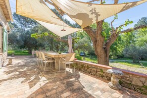 Un patio al aire libre con una mesa, sillas, un muro de piedra y un árbol.