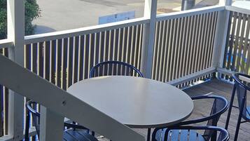 Relax in an outdoor seating area with a round table and six chairs, overlooking a charming street scene.