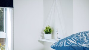 A bedroom with a bed, a hanging plant, and a window. - The Boathouse Lodge (Picton)