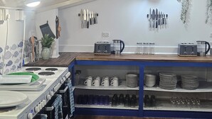 A kitchen with a stove, oven, and various kitchen utensils on the wall. - The Boathouse Lodge (Picton)