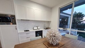 Una cocina moderna con armarios blancos, microondas y lavavajillas. Hay una mesa de comedor con un centro de mesa original.