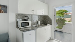 Una cocina compacta con armarios blancos, encimera de granito, microondas, fregadero y lavavajillas.