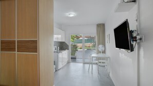 Una habitación moderna con cocina, comedor y televisor montado en la pared.