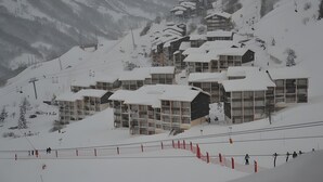 Un centro de esquí cubierto de nieve con varios edificios, incluyendo un albergue y un telesilla.