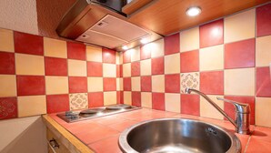 Una cocina con un lavamanos de acero inoxidable, una estufa a gas y un salpicadero de azulejos.