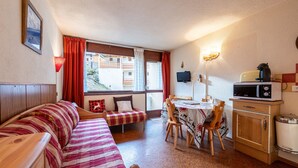 Una habitación acogedora con sofá, una mesita, una silla, microondas y armario.