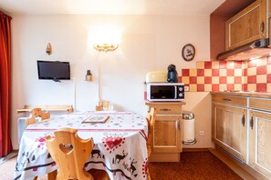 Una cucina compatta con forno a microonde, mobili in legno e un tavolo con una tovaglia festosa.