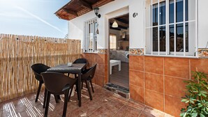 A patio with a table and chairs, a wooden fence, and a building entrance with a number '6D' on the wall.