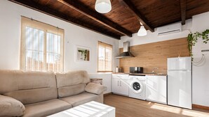 A modern kitchen with a washing machine, a refrigerator, and a wooden ceiling.