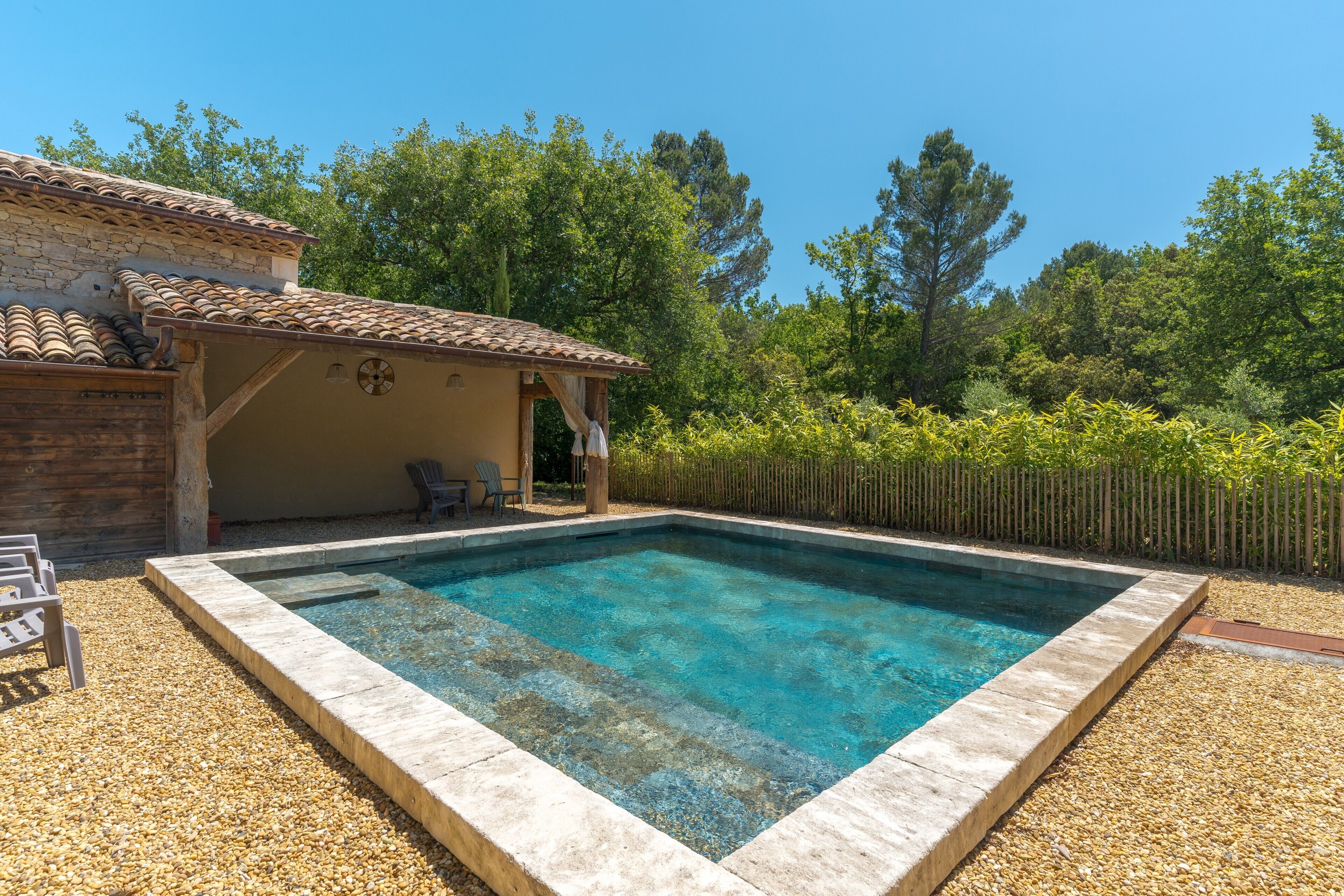 A rectangular swimming pool with a tiled deck, surrounded by pebbles.