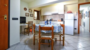 A compact kitchen with a dining area, a refrigerator, and a television on a counter. - Cozy apartment in Trecastagni with swimming pool (Trecastagni)