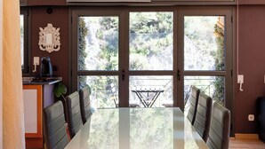 Uma sala de jantar com uma mesa grande, quatro cadeiras e vista para uma varanda com um varal.