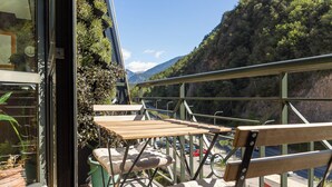 Uma varanda com mesa e cadeiras, com vista para uma paisagem montanhosa.