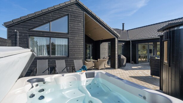 A modern house with a hot tub in the backyard, a covered patio, and a large window. - Lovely home in Vejers Strand with sauna (Vejers Strand)