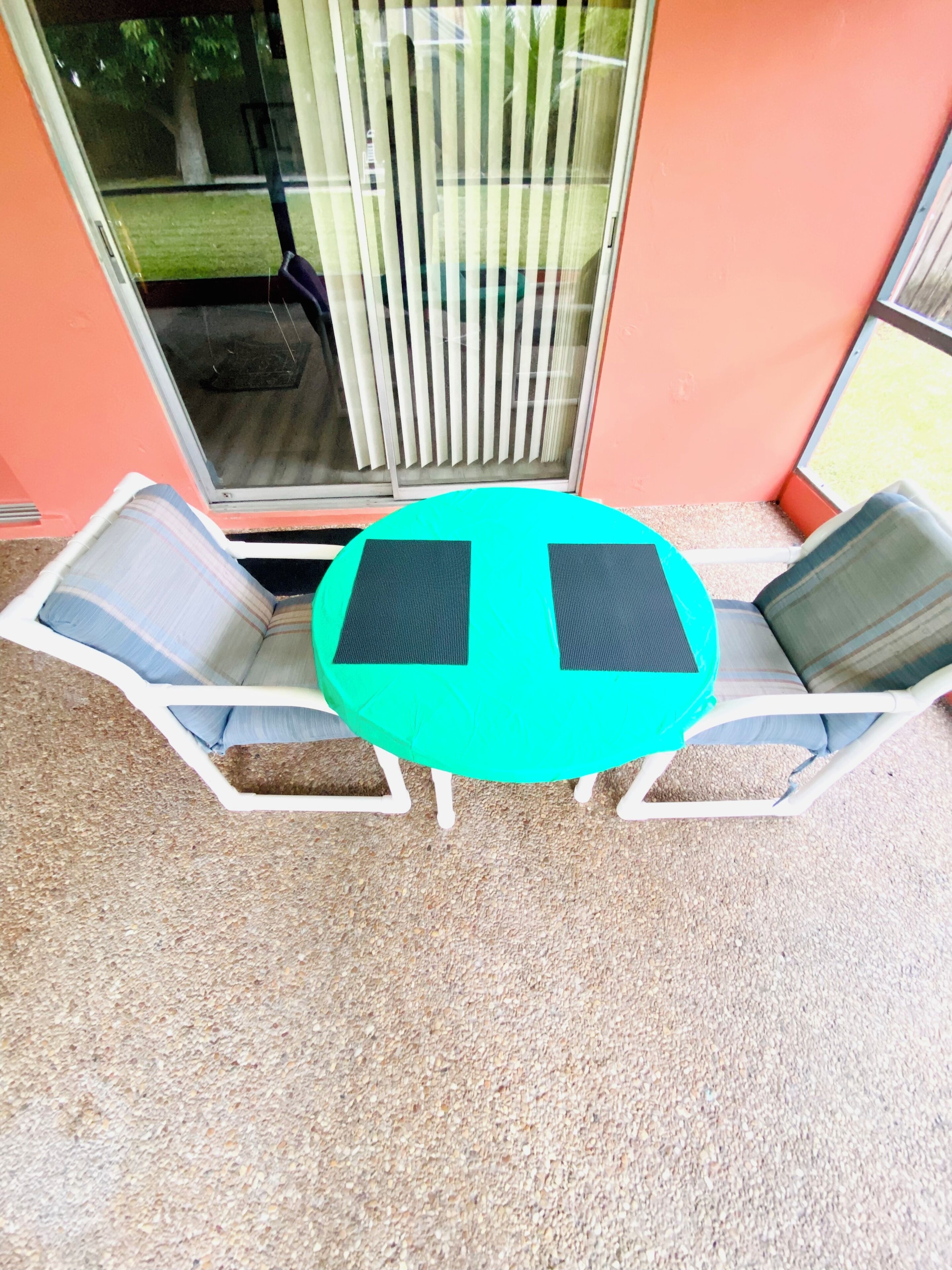 A small patio area with a round table and two lounge chairs.