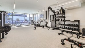 Een moderne fitnessruimte met cardioapparatuur, gewichten en dumbbells.
