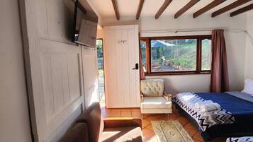 Una habitación compacta con sofá, cama, una mesita y televisor instalado en la pared.