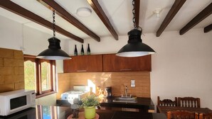 Una cocina con una isla de ladrillo, armarios de madera e iluminación colgante.