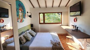 Un dormitorio con cama, escritorio, televisor y ventana.