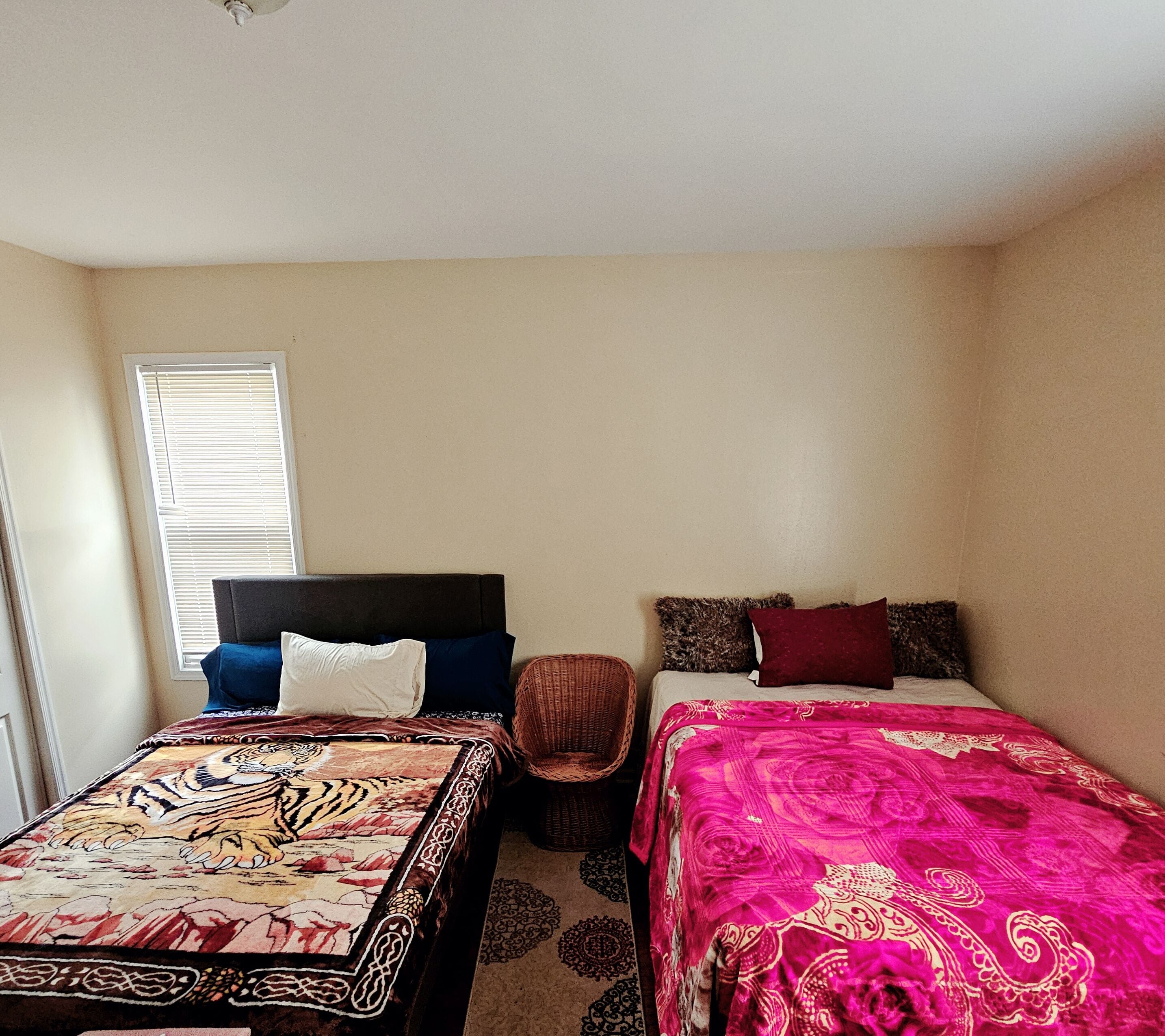 A bedroom with two beds, each with distinct patterned bedspreads.