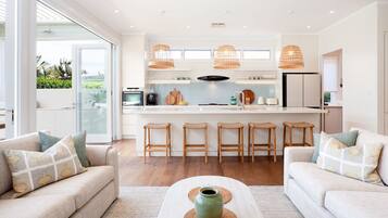 A modern kitchen with a central island, bar stools, and a view to the outdoors.